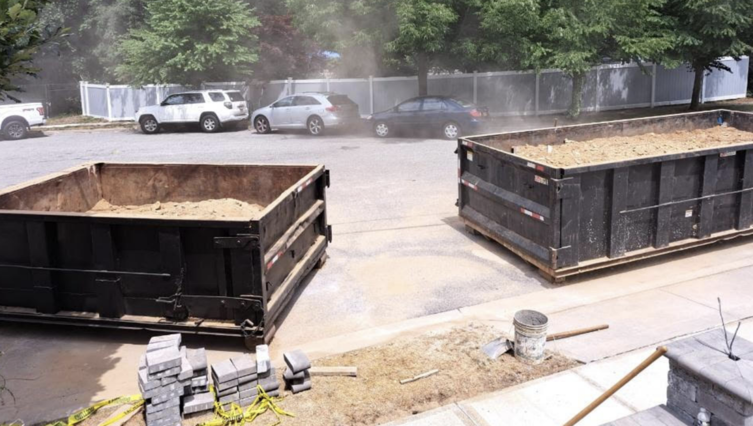 Two empty dumpsters on the street near a construction site
