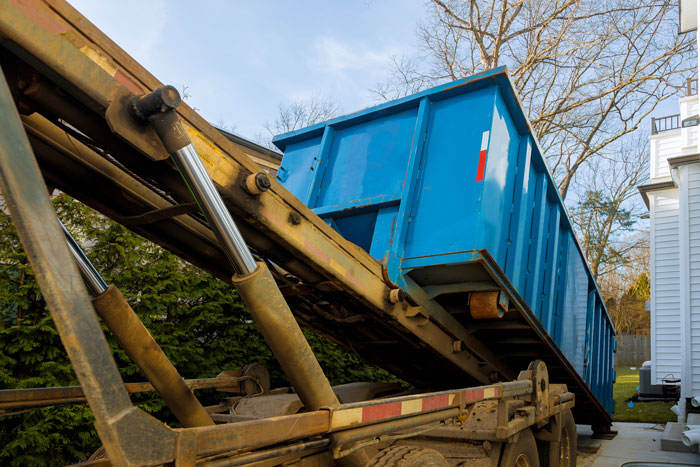 Unloading of empty roll off dumpster near a residential house being built and construction garbage