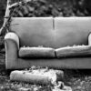 old couch on the front lawn covered in leaves, black and white photo.